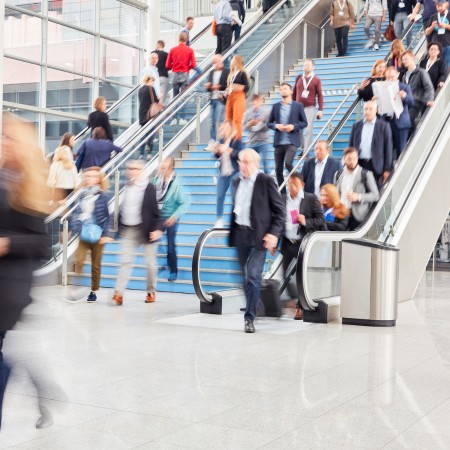 Menge Business Leute auf Rolltreppe in Messehalle