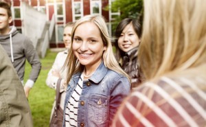 Jugendliches Mädchen lächelt in die Kamera umgeben von anderen Jugendlichen