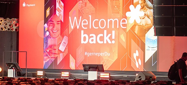 große Leinwand im Hintergrund mit Schriftzug "Welcome back!", Stühle im Vordergrund Payment-Symposium 2025 Rückblick